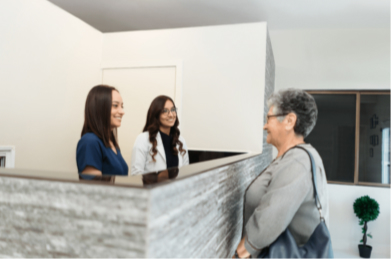 aged woman talking to 2 woman in the front desk of dental clinic